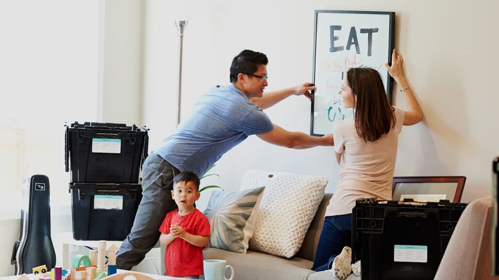 man and woman hanging art of the wall with a child nearby