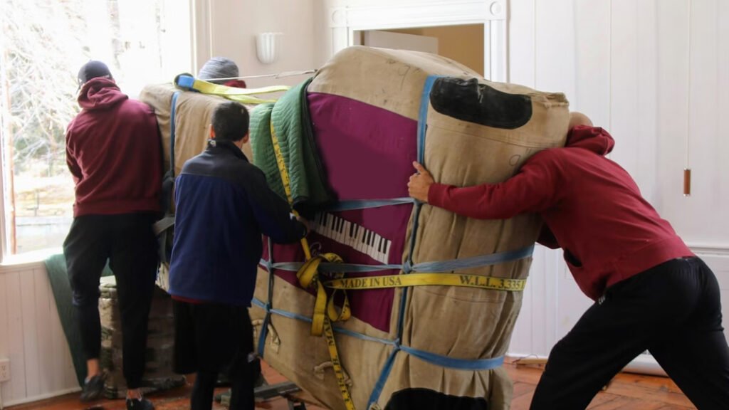 three people moving a piano